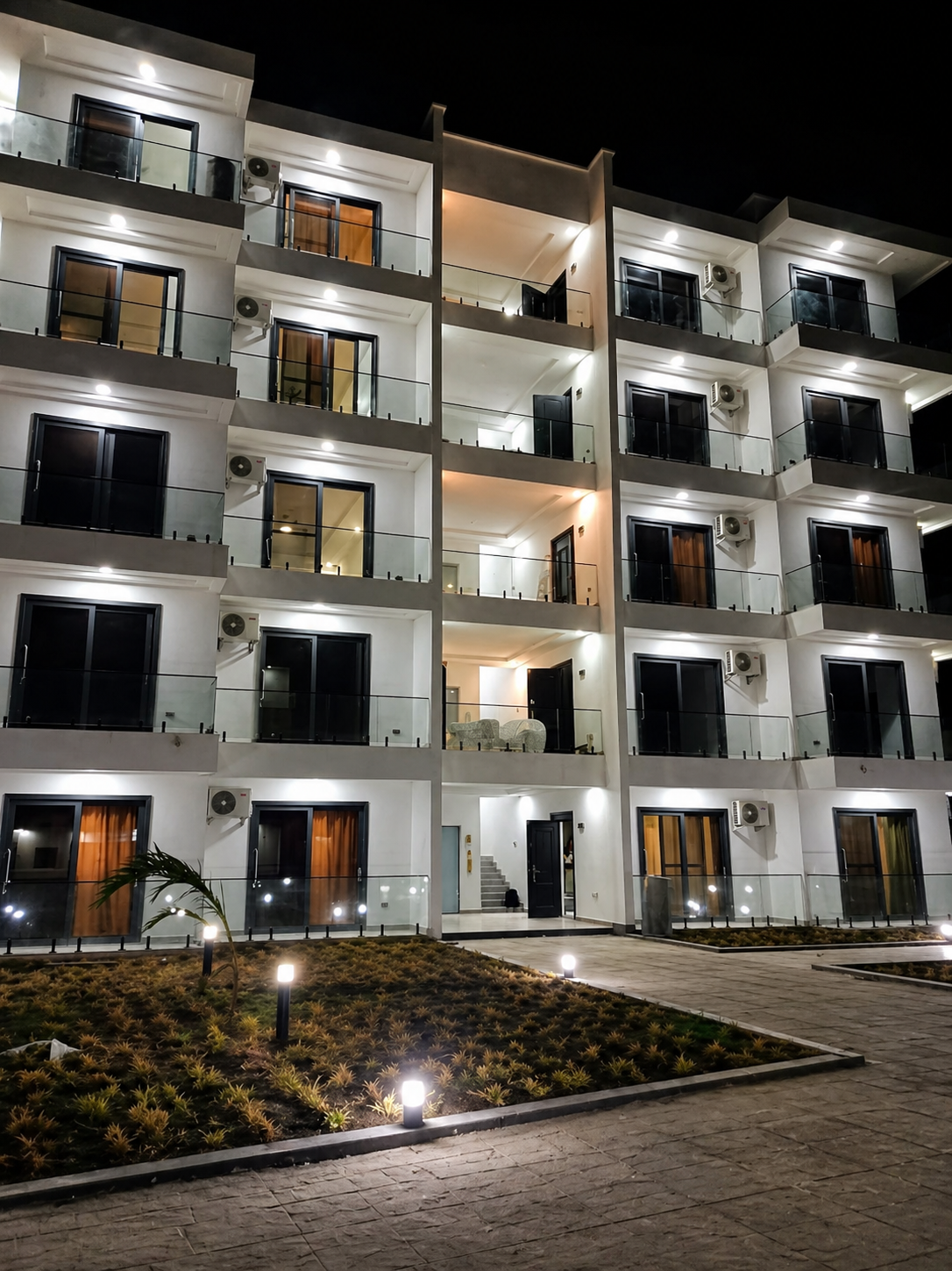 Résidence TECHNOBAT illuminée de nuit — façade premium, balcons en verre, programme livré à Dakar